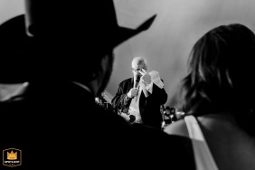 Sentimental Toast: Kansas City Mansion Wedding Photo Features Father's Loving Gesture At a wedding reception in a Kansas City mansion, the father stands behind the couple during toasts. The photo captures the moment, with the couple's heads in the foreground.